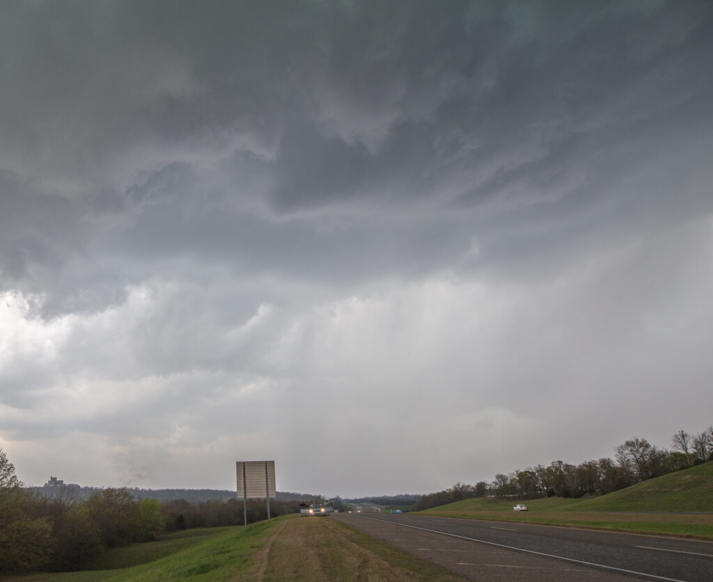 Funnel above, dust whirl on the ground to the left of the road